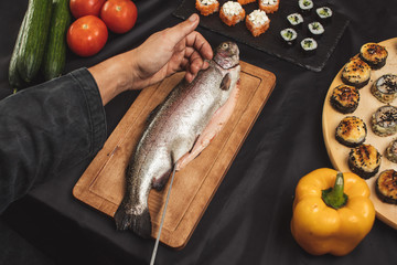 Wall Mural - man's hands cutting fish fillet in the restaurant. close up top view photo. seafood, healthy food