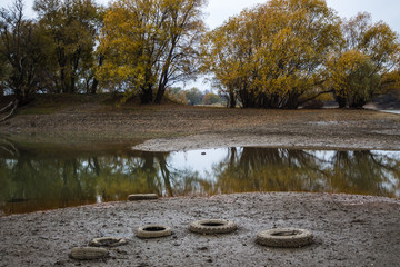 On the banks of the river are car tires. Environmental pollution