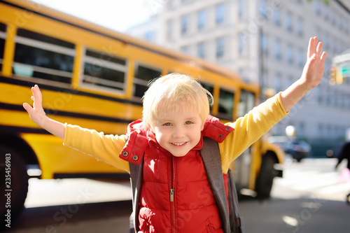 Fototapeta Pupil with schoolbag with yellow school bus on background
