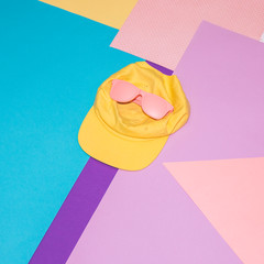 Wall Mural - Pink sunglasses and yellow cap on colorful background. Memphis style