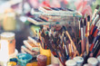 Leinwandbild Motiv Paint brushes and watercolor paints on the table in a workshop, selective focus, close up.