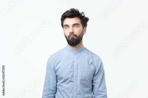 Fotomural Weary hispanic man in blue shirt rolling his eyes up