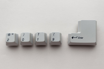 Computer keyboard keys with 2019 enter written using the white buttons on a neutral grey background. New year technology concept. New year 2019 card with copyspace.