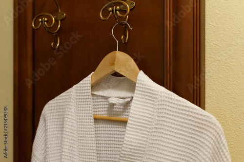 Fotografie, Obraz White textile robe is hanging on the hook in the bedroom