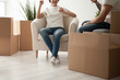 Happy young couple drinking juice in new apartment while unpacking boxes with belongings, family just arrived in new own house, man and woman relaxing in living room, preparing to moving close up