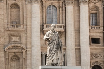 The statue of St. Peter, who holds the key to heaven. St. Peter's Basilica in the background. Vatican, Rome, Italy.