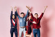 © Leika production - Cheerful company of two girls and two guys dressed in stylish clothes are standing and having fun with confetti on a pink background in the studio