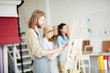 © pressmaster - Contemporary young artist standing in front of easel in studio while sketching on paper