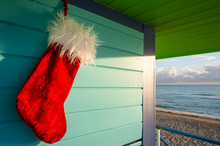Santa Stocking Christmas Decoration Hanging From Brightly Colored Lifeguard Tower Next To Calm Tropical Seas In Miami Beach, Florida, USA