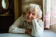 Leinwandbild Motiv Portrait of elderly pensioner lady sitting at the table.