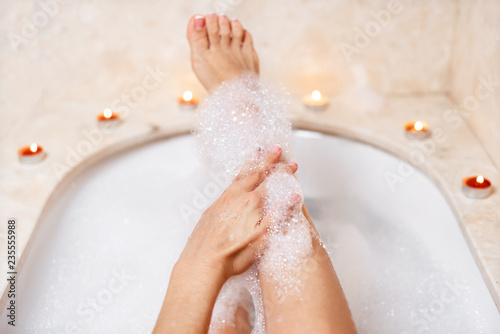 Fotografía Woman legs in bath foam. Relaxation in spa.