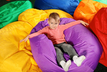 Cute Child Playing On Colorful Bean Bag Chairs Indoors