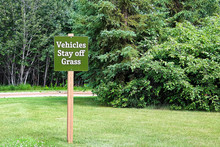 A Green Vehicles Stay Off The Grass Sign