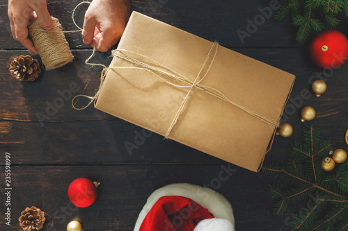 Fotografía Man wrapping christmas present table Rustic background Wrapping top view