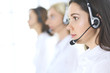© rogerphoto - Group of call center operators at work. Focus on beautiful business woman in headset