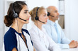 © rogerphoto - Call center operators at work. Focus at beautiful latin american woman in headset