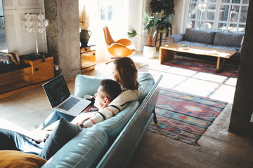 Happy couple domestic life situation. Husband and wife in love together watching laptop on sofa