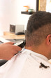 © Anna - Back view of man getting short hair trimming at barber shop with clipper machine