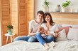 © Aleksandr - young parents with a newborn baby at home on the bed
