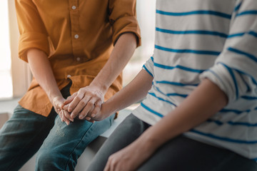 Psychologist sitting and touch young depressed asian woman for encouragement near window with low light environment, Selective focus, PTSD Mental health concept,