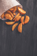 Wall Mural - Baked fried potatoes on black wooden background. Top view. Toned photo