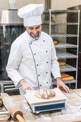 Wall Mural - smiling baker weighing raw dough on kitchen scales