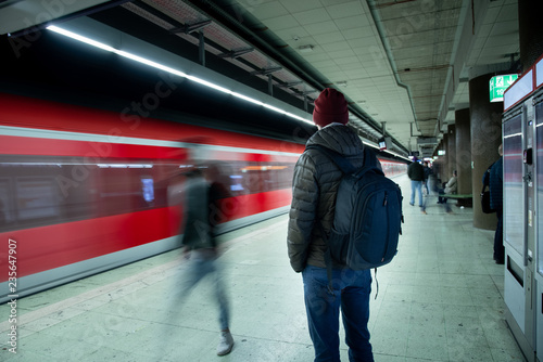 Fotografie, Obraz Mann mit Rucksack wartet auf den Zug am Bahnhof