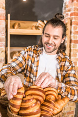 Wall Mural - Handsome seller putting pastry in wicker basket