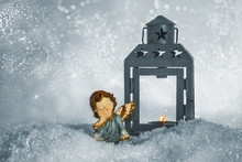 Christmas Angel And A Lantern With A Candle On A Snow On A Sparkling Silver Background