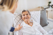 © Halfpoint - A health visitor talking to a sick senior woman lying in bed at home.