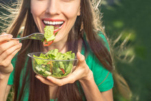 Beautiful Caucasian Woman Eating Salad Over Green Natural Background	