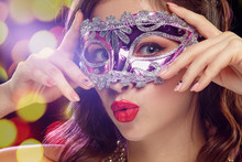 Beauty Model Woman Wearing Venetian Masquerade Carnival Mask At Party Over Holiday Dark Background With Magic Glow. Christmas And New Year Celebration. Glamour Lady With Perfect Make Up And Hairstyle