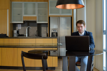 Young handsome businessman sitting in the dining room near the k