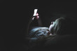 © Brian - Depressed girl lying down on a couch in the dark while using her smartphone. The light from the screen is illuminating her face.