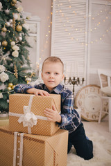 Little boy with gift box near Christmas tree on Christmas eve at home.Child babyboy in light room with winter decoration.Happy family at home.Christmas New Year december time for celebration concept