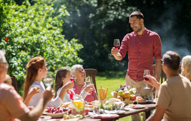 leisure, holidays and people concept - happy family having festive dinner or summer garden party and celebrating