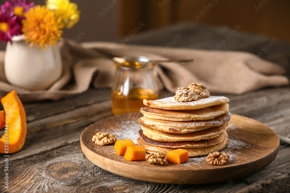 Stack of hot pumpkin pancakes with sugar powder on wooden plate