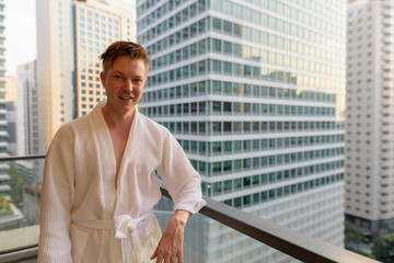 Young handsome man enjoying the view of the city from the balcon