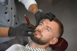 © serhiibobyk - View from above of man on chair while barber shaving beard
