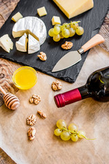 bottle of red wine, appetizers and corkscrew on wooden backgroun