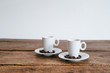 2 Espresso Tassen mit Kaffee Bohnen auf Unterteller Holztisch Hintergrund weiß