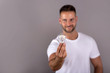 © Spectral-Design - A smiling young man in a white tshirt holding a lightbulb and standing in front of a grey background in the studio.