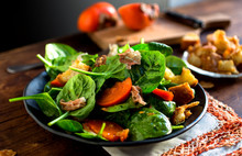 Spinach Salad With Prosciutto, Persimmon And Parmesan Croutons Served On Plate
