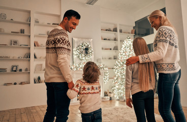 Poster - The happy parents with kids standing on the christmas tree background