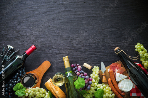 Fotografía Wine bottles with grapes, cheese, ham and corks