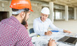 © xartproduction - male engineers, architects working at the desk in helmets. Drawings, laptop, roulette on the desktop. Reception and supervision of building construction