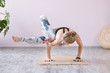 Yoga woman training on exercise mat and doing balance yoga poses. Astavakrasana or asymmetrical arm balance pose. Wellness and healthy lifestyle