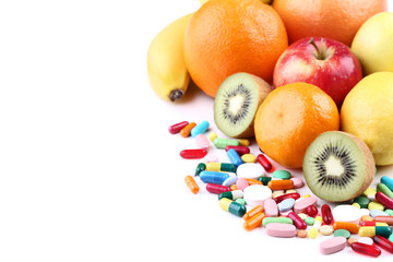 Ripe fruits and colorful pills on white background