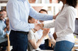 © fizkes - Middle aged boss, mentor congratulating African American female employee, intern, praise for good work, idea for startup, shaking hand, welcoming new member of business team, colleagues applauding