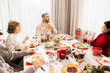© Seventyfour - Warm-toned portrait of big happy family enjoying Christmas dinner together, end exchanging presents at table